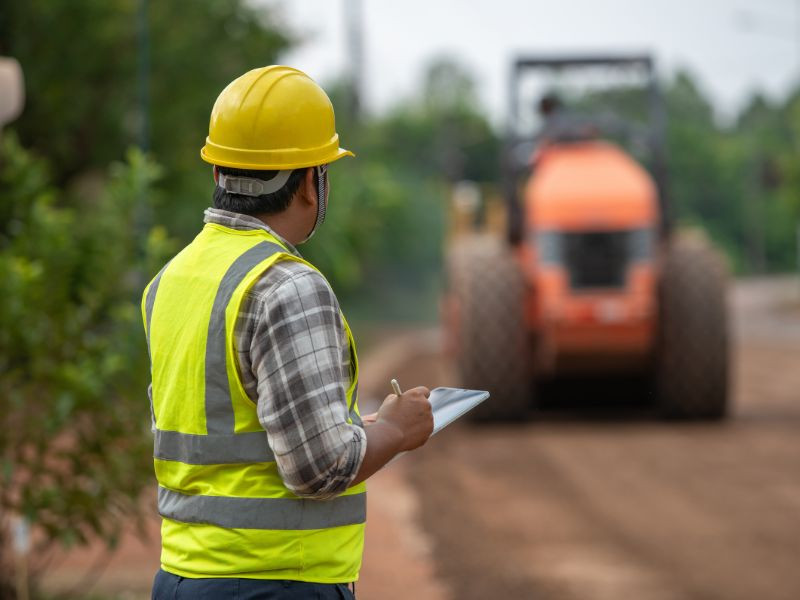 Supervisor observando el trabajo de maquinaria pesada de una marca confiable en un proyecto de construcción.