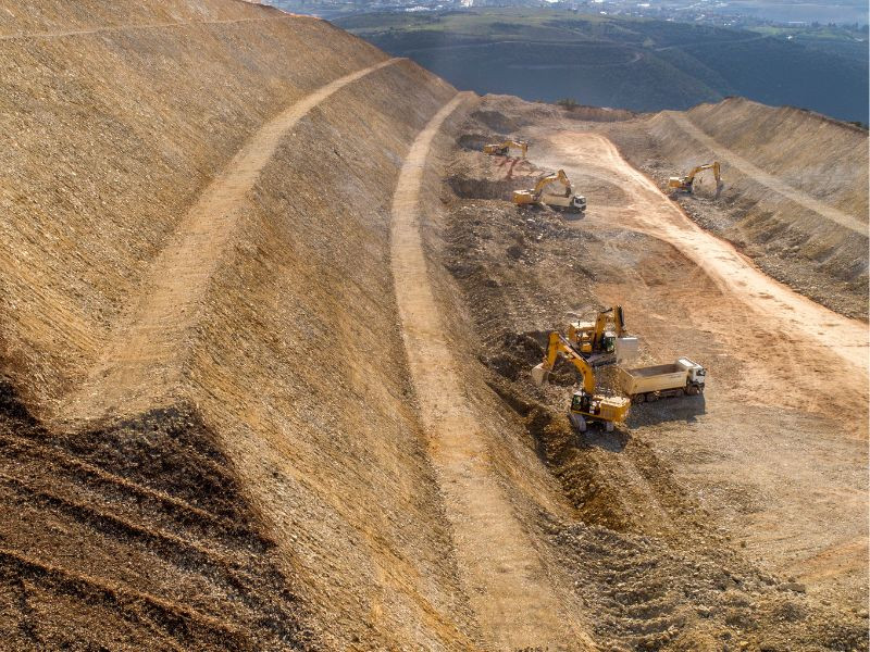 Excavadoras y camiones en movimiento de tierras durante la construcción de una carretera.