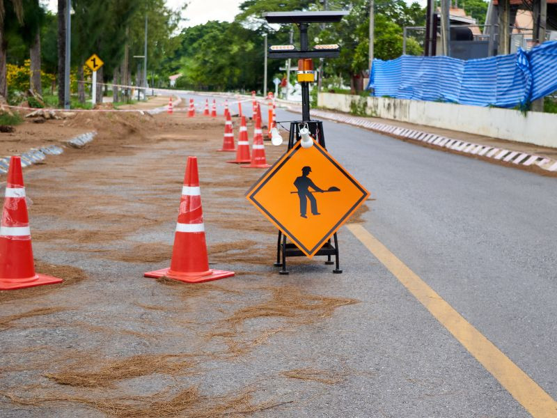 Señal de advertencia de obras en carretera con conos de tráfico en un tramo en reparación.