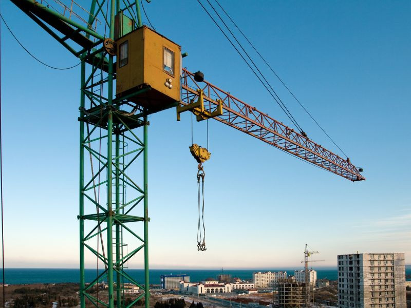 Grúa torre utilizada para levantar materiales pesados en la construcción de un edificio alto.