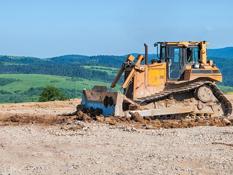 Bulldozer nivelando terreno en una obra de construcción, utilizado para mover y despejar grandes volúmenes de tierra.